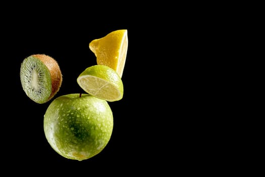 Green fresh organic fruits halves on black background