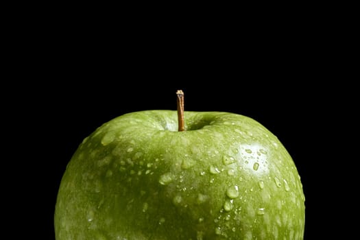 Close up of green organic fresh apple with water drops on black background