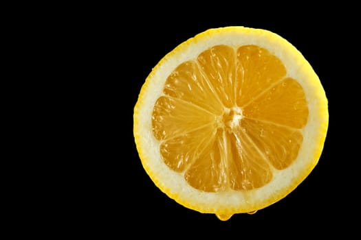 Closeup of fresh yellow organic half lemon with water droplets on black background