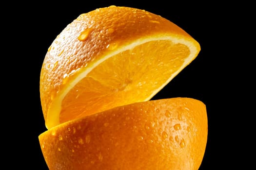 Two fresh halves of orange with water droplets on black background