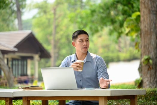 Portrait of asian man entrepreneur drinking coffee and working with laptop at outdoor.