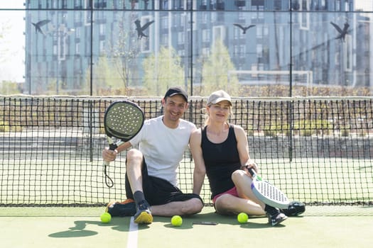 Sports couple with padel rackets posing on tennis court. High quality photo