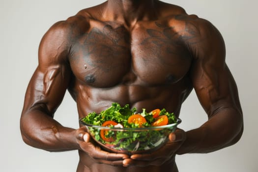 Portrait of strong male athlete torso holding a green salad. Concept of healthy food and lifestyle.