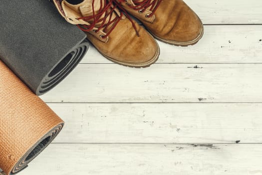Hiking boots with travel accessories on grunge background