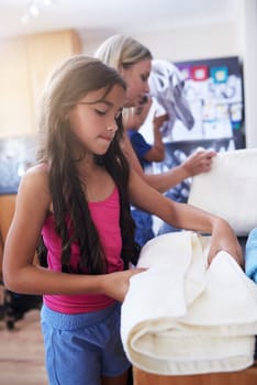 Children, mother and laundry with towels for chores to learning responsibility at home. Daughter, woman and teamwork with cleaning house by helping, bonding and cooperation together for growth.