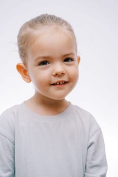 Little smiling inquisitive girl on a gray background. Portrait. High quality photo