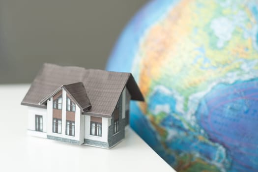 House miniature with globe in background against plain wall. High quality photo