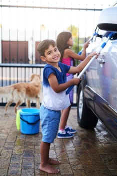 Children, fun and home and washing car, portrait kids cleaning motor vehicle with equipment. Siblings, driveway and helping with responsibility together on weekend, happy in outdoor for chore.