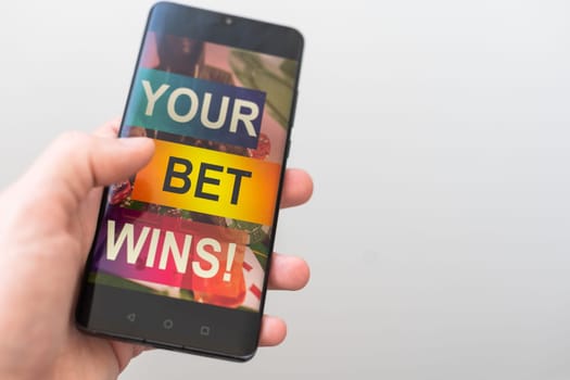 Male's hand holds smartphone with bet application. Victory message. Betting concept. High quality photo
