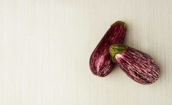 Eggplant, nutrition and vegan food on table top for wellness, health and diet in studio. Aubergine, green and purple isolated for eating, ingredients and mockup space in house for above and cook