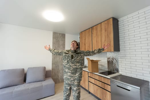 Patriotic military man in uniform keeps box in new apartments. Buying a property.