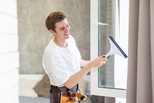 Young man washing window in office.