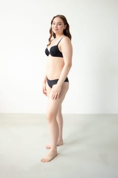 young woman with beautiful hair in black lingerie posing isolated on white background. Model test, snap, polaroid