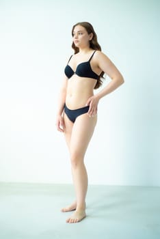 young woman with beautiful hair in black lingerie posing isolated on white background. Model test, snap, polaroid