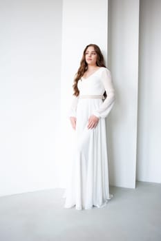 portrait of beautiful young woman in white wedding dress posing in studio