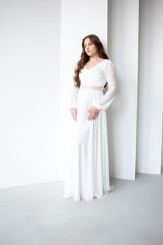 portrait of beautiful young woman in white wedding dress posing in studio