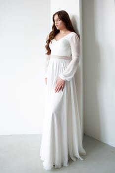 portrait of beautiful young woman in white wedding dress posing in studio