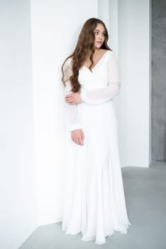 portrait of beautiful young woman in white wedding dress posing in studio