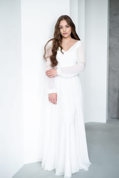 portrait of beautiful young woman in white wedding dress posing in studio