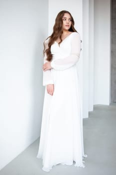 portrait of beautiful young woman in white wedding dress posing in studio