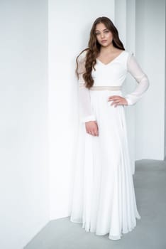 portrait of beautiful young woman in white wedding dress posing in studio