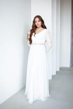 portrait of beautiful young woman in white wedding dress posing in studio