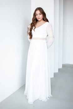 portrait of beautiful young woman in white wedding dress posing in studio