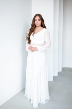 portrait of beautiful young woman in white wedding dress posing in studio