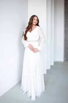 portrait of beautiful young woman in white wedding dress posing in studio