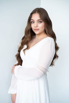 portrait of beautiful young woman in white wedding dress posing in studio