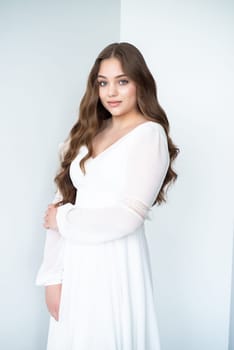 portrait of beautiful young woman in white wedding dress posing in studio