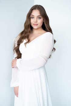 portrait of beautiful young woman in white wedding dress posing in studio