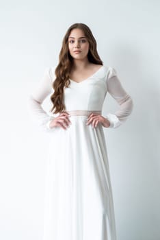 portrait of beautiful young woman in white wedding dress posing in studio