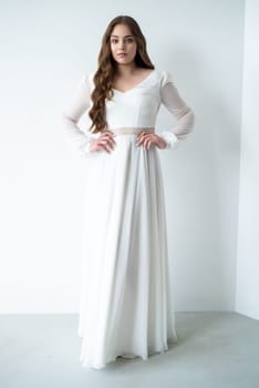 portrait of beautiful young woman in white wedding dress posing in studio