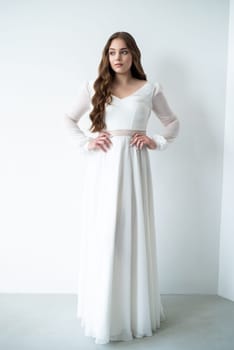 portrait of beautiful young woman in white wedding dress posing in studio