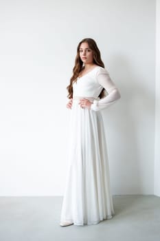 portrait of beautiful young woman in white wedding dress posing in studio