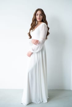 portrait of beautiful young woman in white wedding dress posing in studio