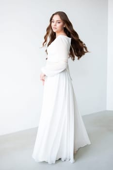 portrait of beautiful young woman in white wedding dress posing in studio