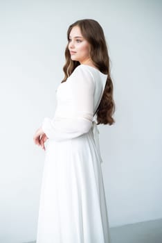 portrait of beautiful young woman in white wedding dress posing in studio