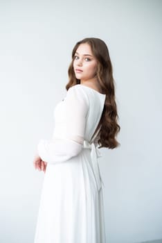 portrait of beautiful young woman in white wedding dress posing in studio