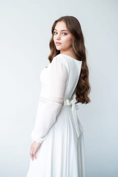 portrait of beautiful young woman in white wedding dress posing in studio