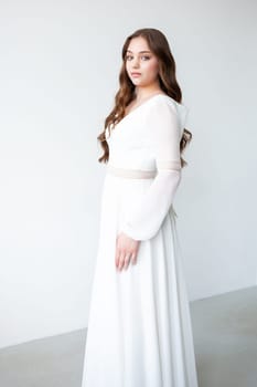 portrait of beautiful young woman in white wedding dress posing in studio