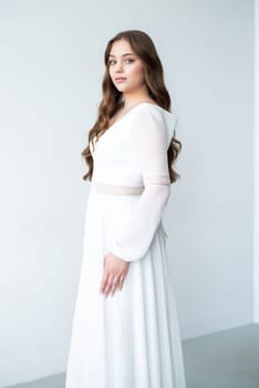 portrait of beautiful young woman in white wedding dress posing in studio