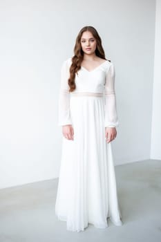 portrait of beautiful young woman in white wedding dress posing in studio