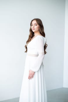 portrait of beautiful young woman in white wedding dress posing in studio