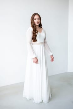 portrait of beautiful young woman in white wedding dress posing in studio