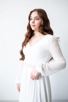 portrait of beautiful young woman in white wedding dress posing in studio