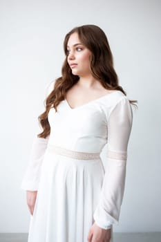 portrait of beautiful young woman in white wedding dress posing in studio