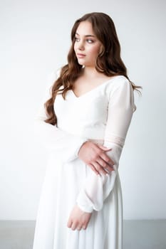 portrait of beautiful young woman in white wedding dress posing in studio