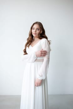 portrait of beautiful young woman in white wedding dress posing in studio